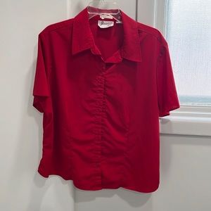 Red colored blouse with short sleeves and buttons in the front.